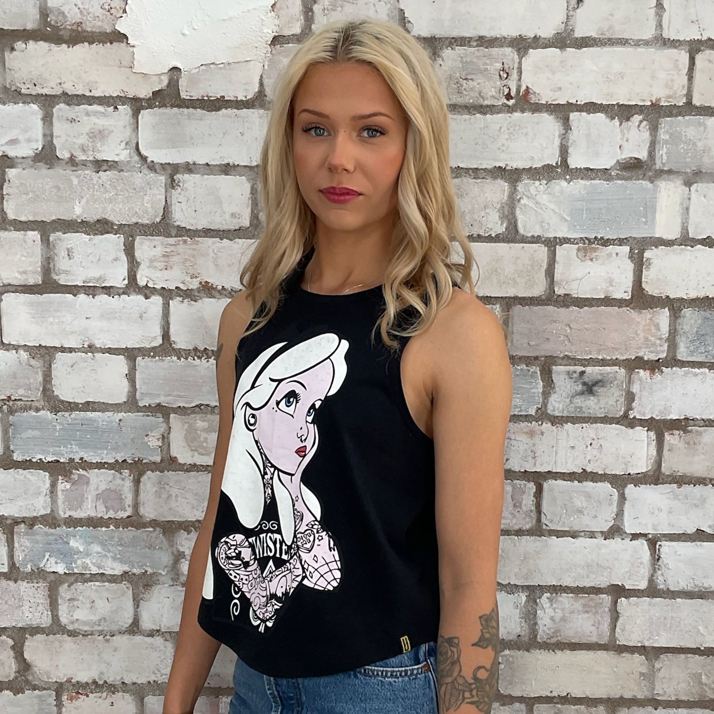Fairytale tattoo Alice in Wonderland with tattoos graphic tshirt upcycled by Unwantees, recycled racerback tank top, upcycled in the UK by unwantees. Sustainable fashion brand Unwantees recycled fairytale tshirt otherwise destined for landfill. Sustainable upcycled fashion, punk and rock Music Style, sleeveless tank top, sustainable upcycled fashion, British recycled fashion brand, slow fashion, eco conscious fashion