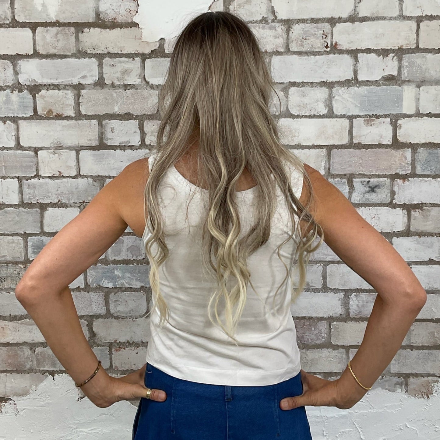 Woman standing with hands on hips in front of a partially painted brick wall