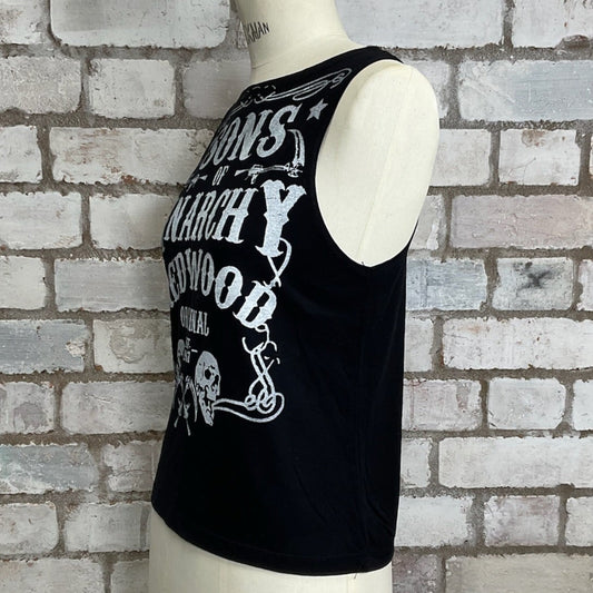 Black tank top with white text on a mannequin against a brick wall.