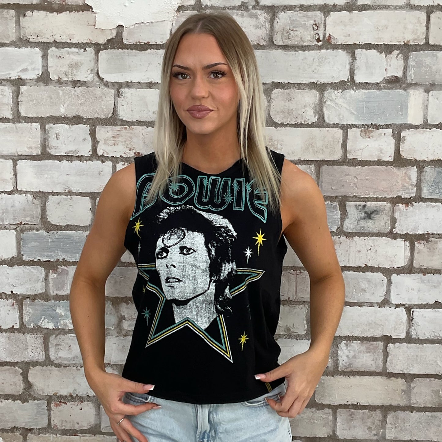 Woman wearing a black Bowie tank top with graphic design against a brick wall. sustainable fashion
upcycled clothing
eco-friendly fashion
reworked fashion
ethical clothing brand
slow fashion