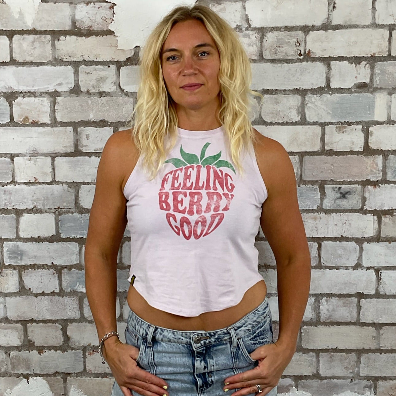 Woman wearing a 'Feeling Berry Good' tank top in front of a textured brick wall. Feeling Berry Good Unwantee, tank top, vest top, recycled fashion by Unwantees