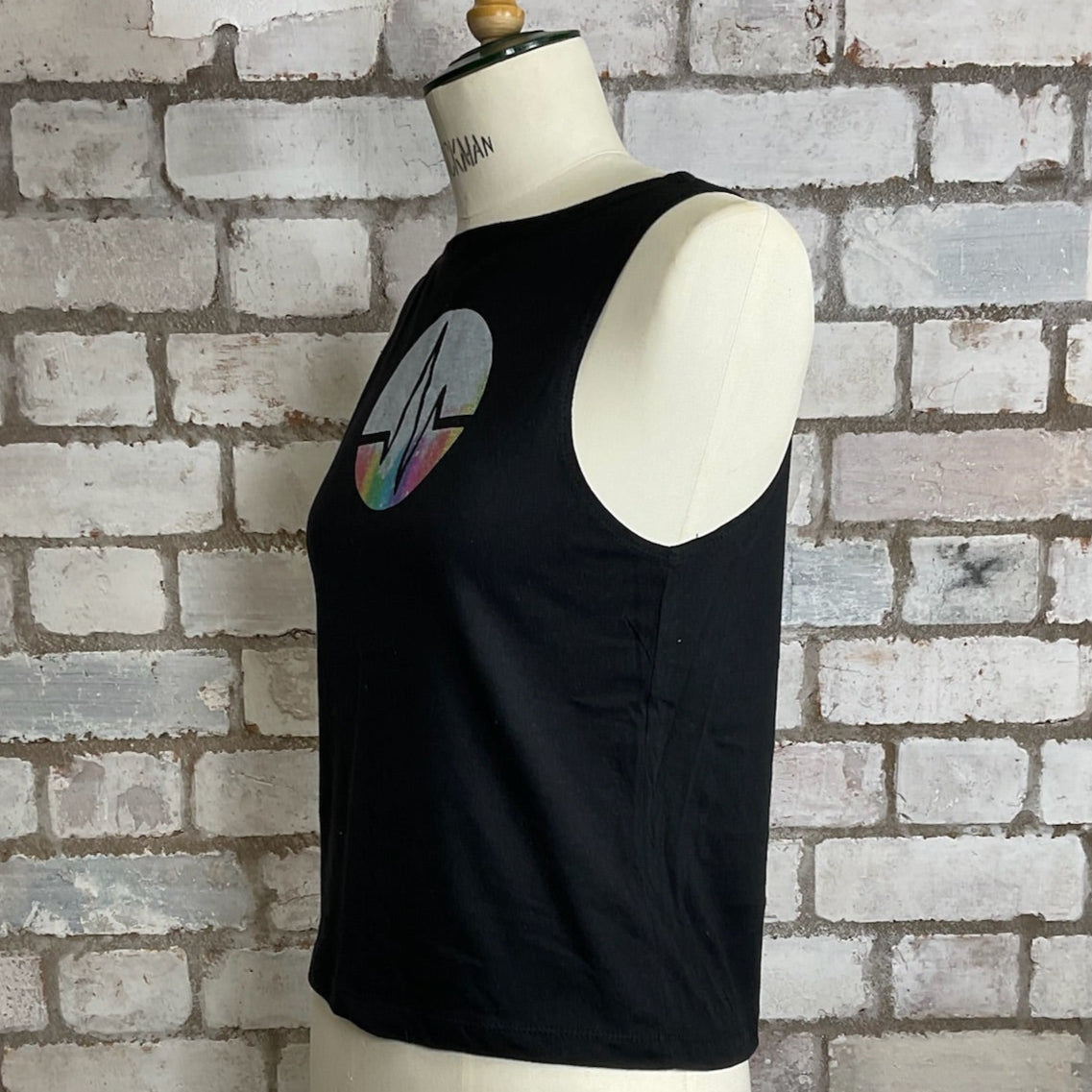 Black tank top with a graphic design on a mannequin against a brick wall. Graphic tshirt up cycle project by Unwantees, Shock wave, heart beat, rhythm, pulse, beat, wave tank top, vest top, Unwantee