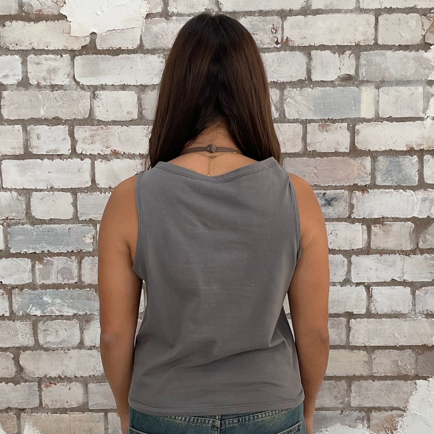 Person wearing a gray tank top against a textured brick wall, sustainable fashion
upcycled clothing
eco-friendly fashion
reworked fashion
ethical clothing brand
slow fashion