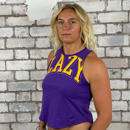 Person wearing a purple tank top with 'LAZY' text in front of a textured brick wall. one of a kind print, Lazy Text tank top, Lazy Purple vest, Message Lazy Unwantees