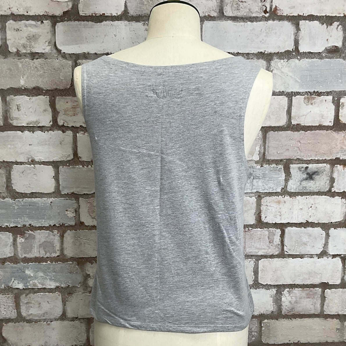 Gray sleeveless top on a mannequin against a brick wall. Unwantees grey slash neck tank top