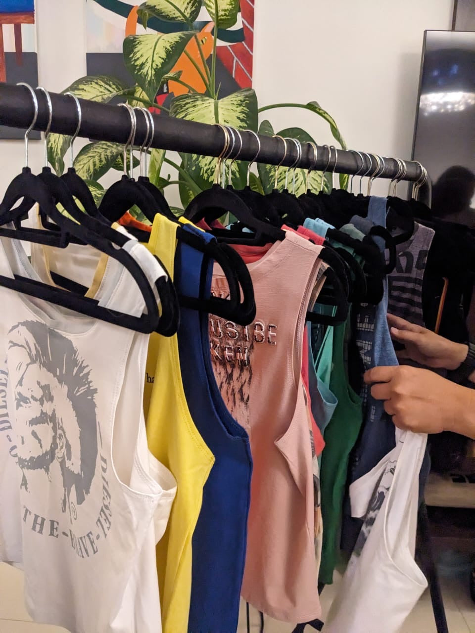Assorted upcycled Unwantees tank tops hanging on a clothes rail