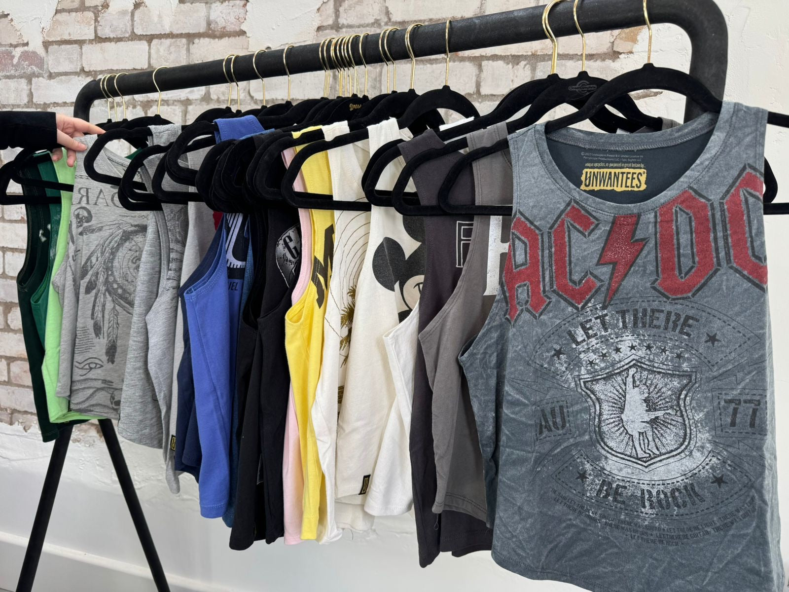 One-of-a-kind upcycled Unwantees tank tops on a clothes rail, with an AC/DC graphic Unwantee at the front