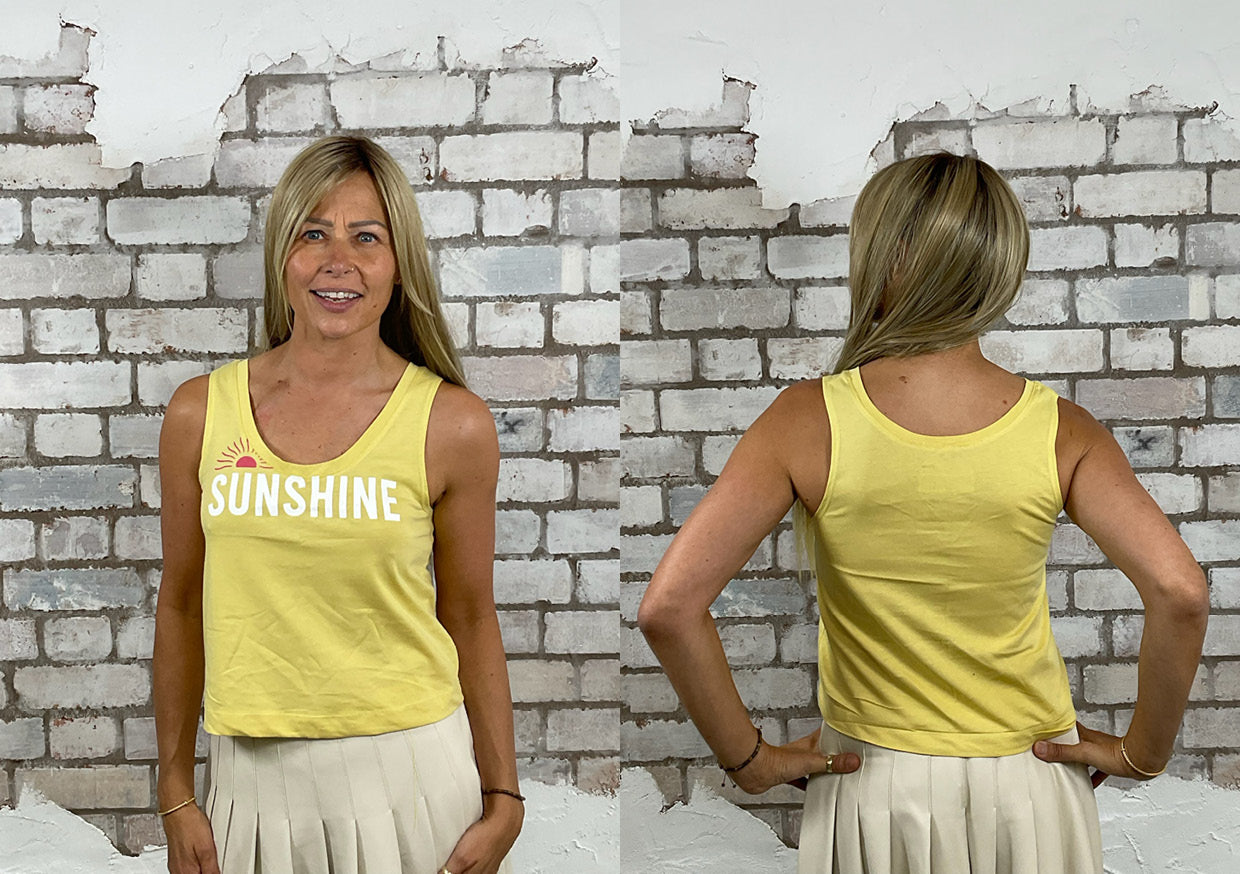Yellow Scoop Neck Unwantee tank top with sunshine design, front and back view on a woman, standing against a white brick wall for fit guide