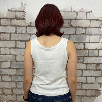 Person wearing a white tank top and blue jeans standing against a textured brick wall.  Marilyn Munroe Diamonds and USA Flag print tshirt upcycled by unwantees, atgleisurewear recycled clothing, sustainable clothing brand