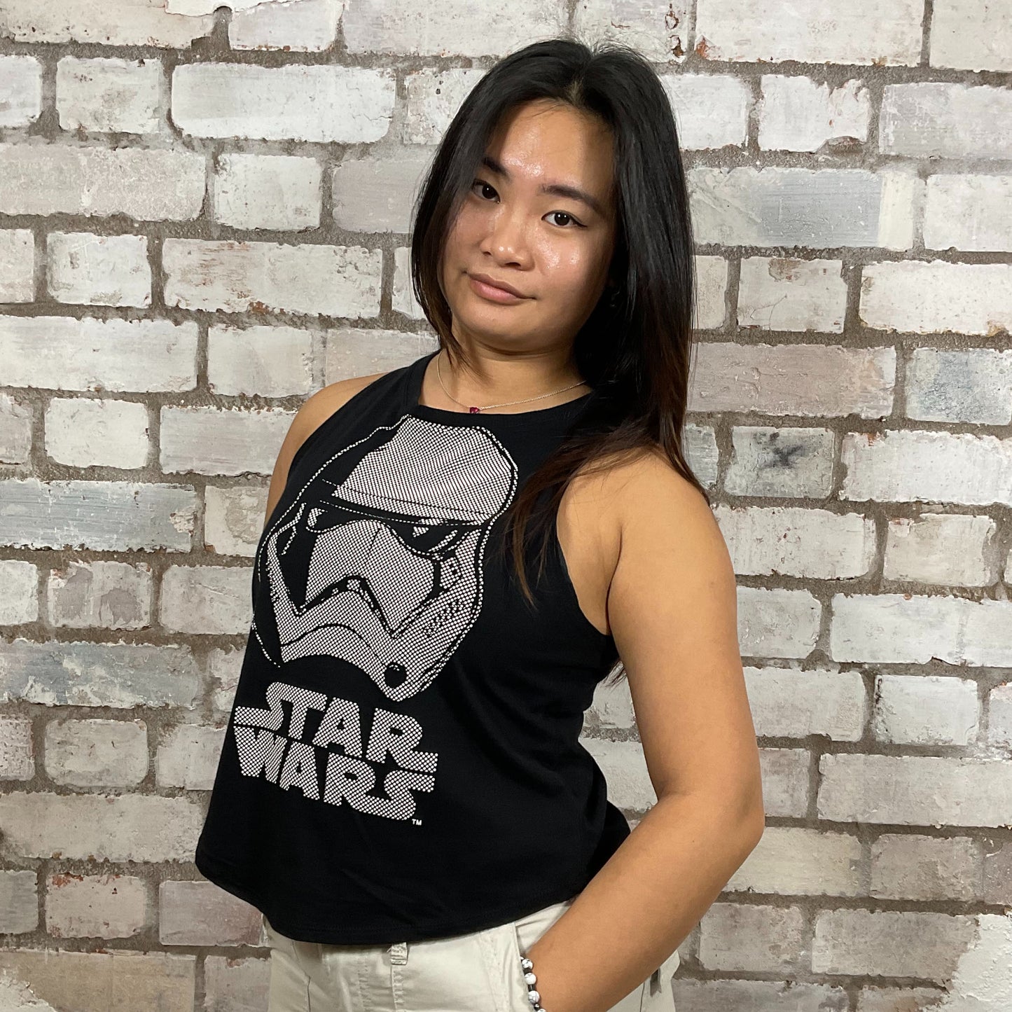 Person wearing a black Star Wars tank top in front of a brick wall.  Storm Trooper Unwantee, recycled tank top made from preloved graphic tshirts, sustainable fashion, eco conscious shopping