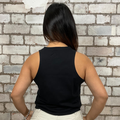 Person wearing a black sleeveless top against a brick wall.  Storm Trooper Unwantee, recycled tank top made from preloved graphic tshirts, sustainable fashion, eco conscious shopping
