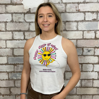 Woman wearing a white tank top with a colorful sun design against a brick wall.  Woman wearing a white tank top with a colorful graphic design against a light brick wall.  sustainable fashion UK
eco-friendly clothing UK
upcycled t-shirts / upcycled tank tops
ethical fashion brand UK
zero waste clothing
slow fashion brand
made in Britain clothing
sustainable vest tops