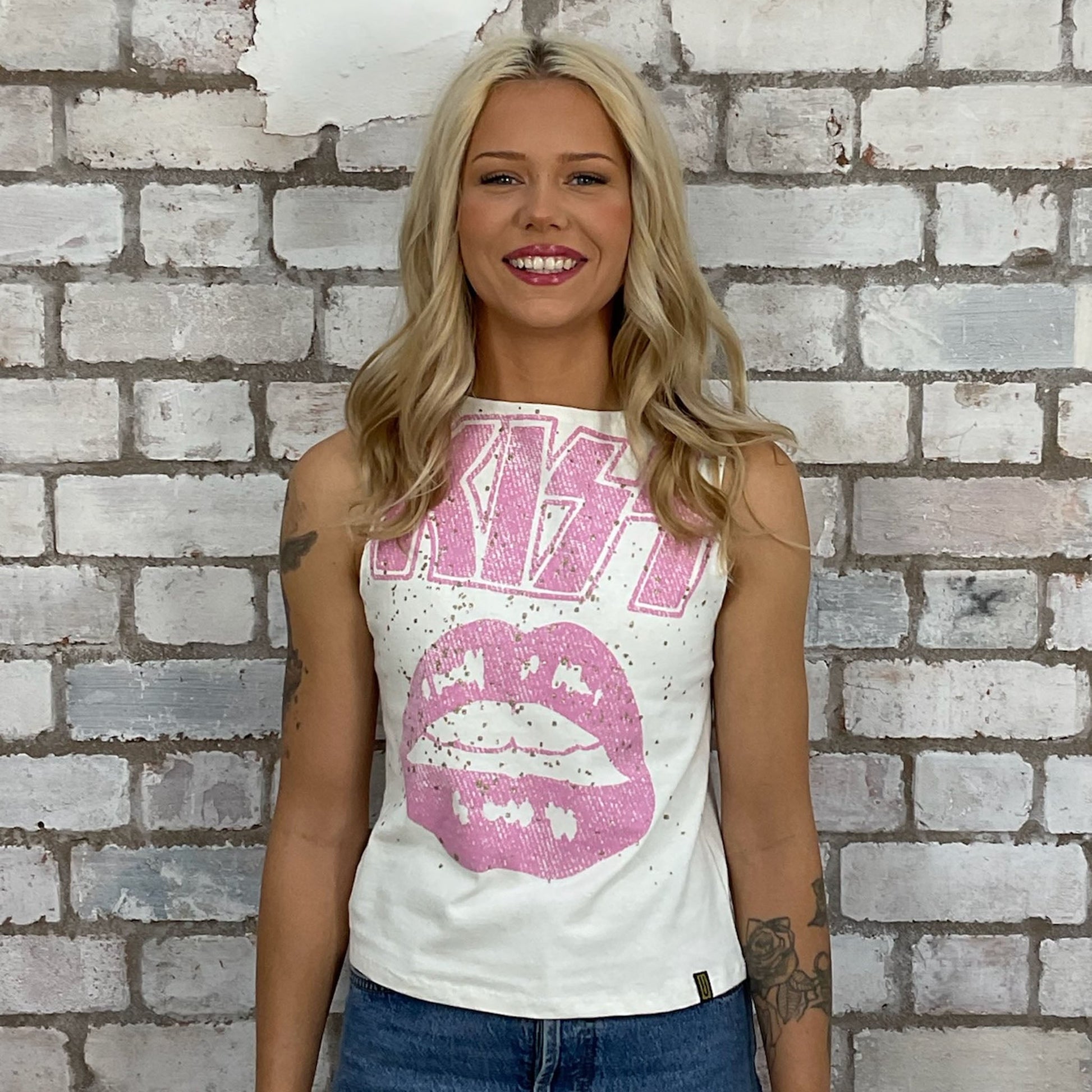 Pink Graphic KISS band tshirt recycled into sleeveless racerback vest top, sustainable upcycled fashion, British recycled grunge brand, slow fashion, Punk Rock music style graphic tshirt upcycled by Unwantees, upcycled in the UK by unwantees. Sustainable upcycled fashion. Graphic tshirt upcycled by Unwantees recycled tshirt otherwise destined for landfill.  