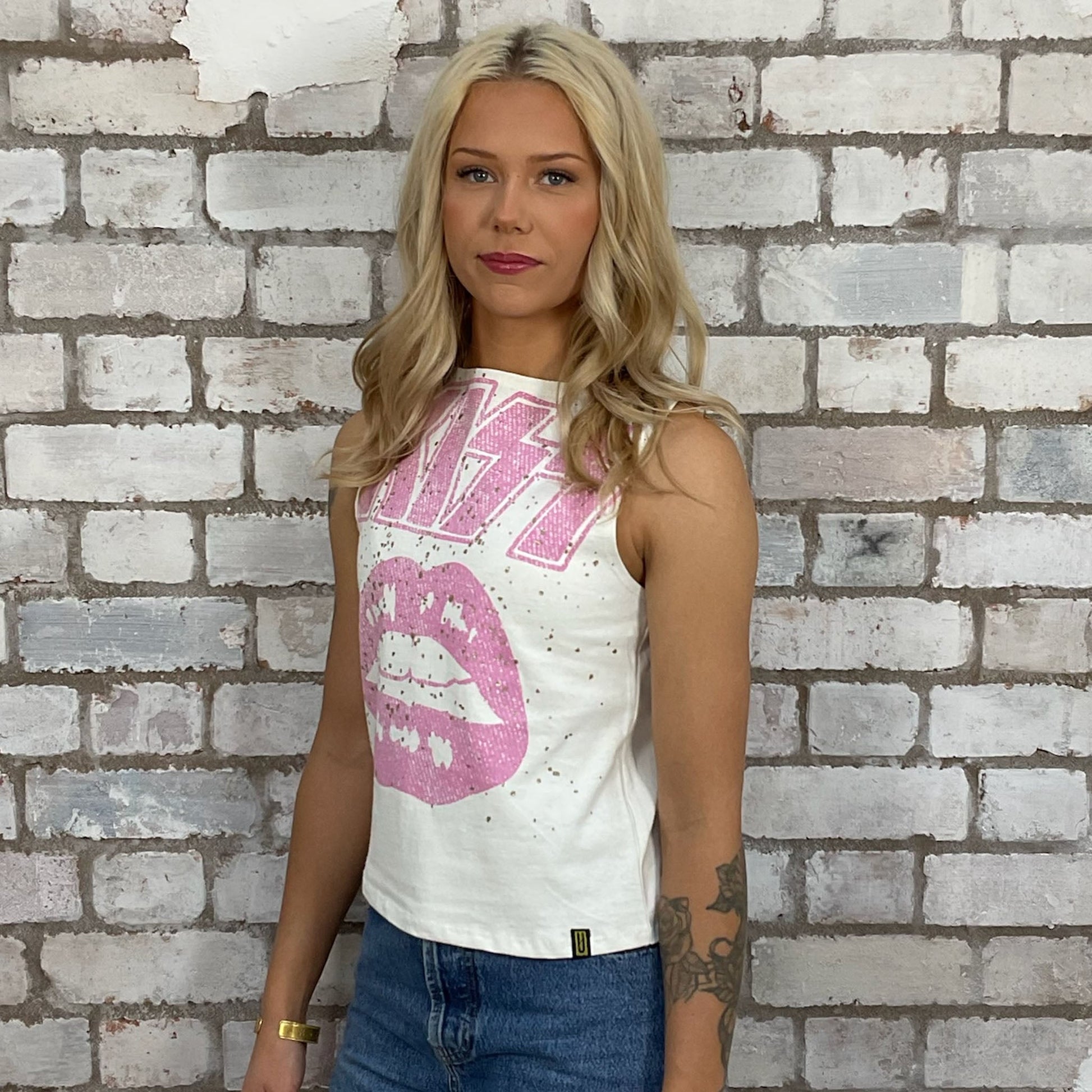 Graphic KISS band tshirt recycled into sleeveless racerback vest top, sustainable upcycled fashion, British recycled grunge brand, slow fashion, Punk Rock music style graphic tshirt upcycled by Unwantees, Pink text on cream tshirt upcycled in the UK by unwantees. Sustainable upcycled fashion. Graphic tshirt upcycled by Unwantees recycled tshirt otherwise destined for landfill.  