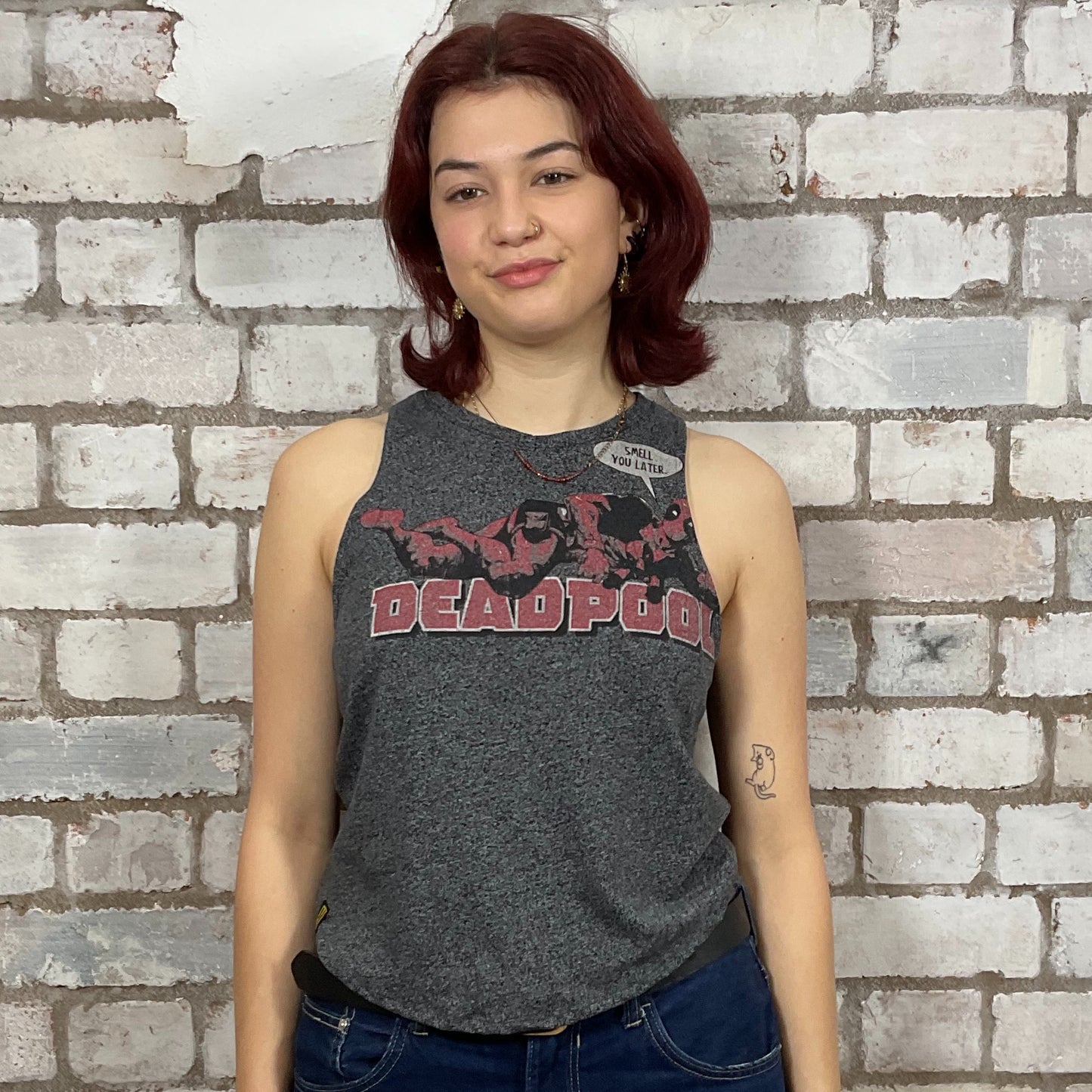 Person wearing a 'Deadpool' tank top against a brick wall.  Dark Grey marl Deadpool Smell you Later Racerback tank top, unwantees, vest top