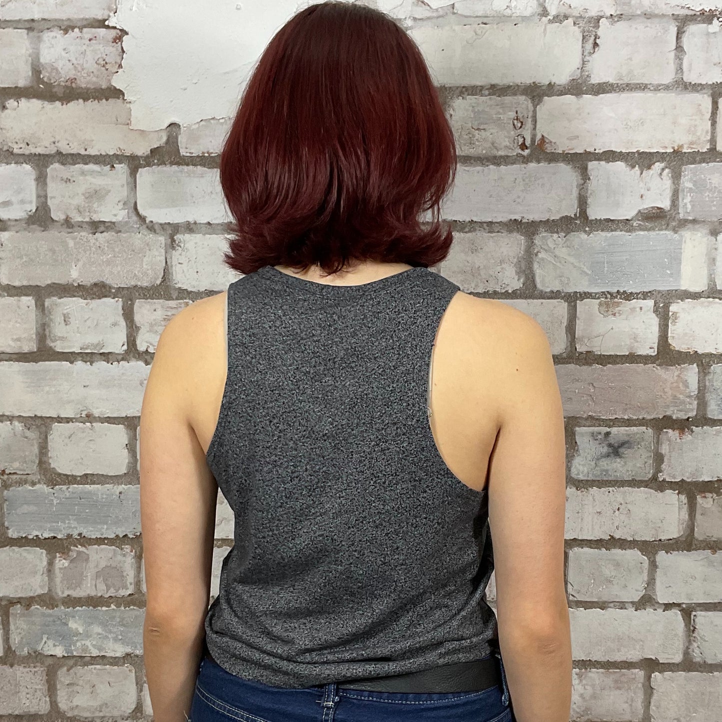 Person wearing a gray tank top against a brick wall.  Dark Grey marl Deadpool Smell you Later Racerback tank top, unwantees, vest top
