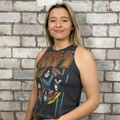 Woman wearing a KISS tank top in front of a brick wall.  KISS Alive Tour 1997 tank top, World Tour KISS Tshirt Upcycle by Unwantees, KISS graphic tshirt, up cycle by Unwantees, www.unwantees.co.uk