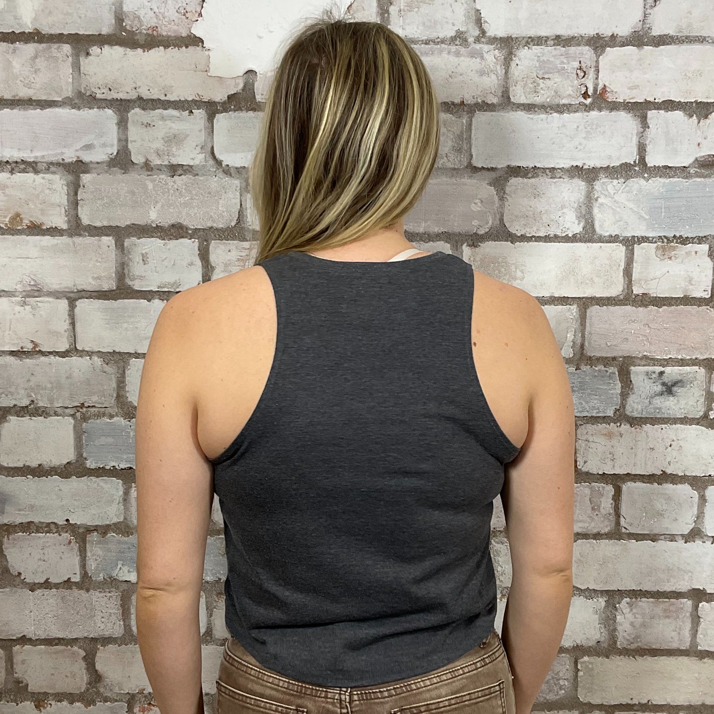 Person wearing a dark gray tank top against a brick wall.  KISS Alive Tour 1997 tank top, World Tour KISS Tshirt Upcycle by Unwantees, KISS graphic tshirt, up cycle by Unwantees, www.unwantees.co.uk