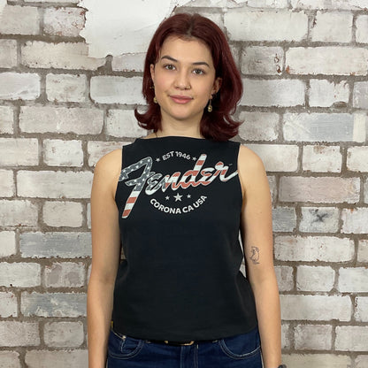 Woman wearing a black sleeveless shirt with 'Fender' logo against a brick wall.  Upcycled fender guitar tshirt by unwantees