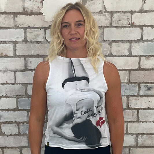 Woman wearing a sleeveless top with a graphic design in front of a textured brick wall. Up cycle project by Unwantees