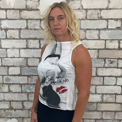 Woman wearing a  vest top with graphic design against a textured wall.  Tank top up cycled by Unwantees