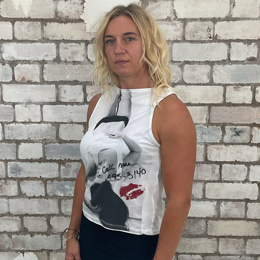Woman wearing a  vest top with graphic design against a textured wall.  Tank top up cycled by Unwantees