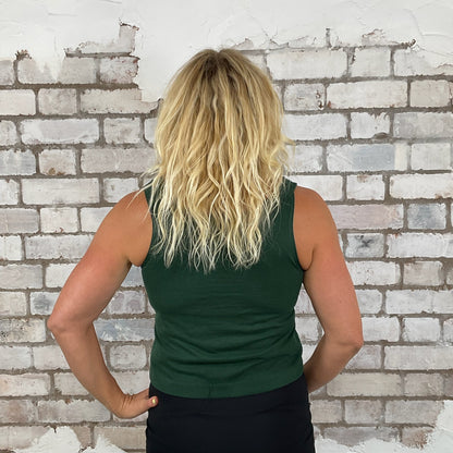 Person wearing a green tank top against a white brick wall