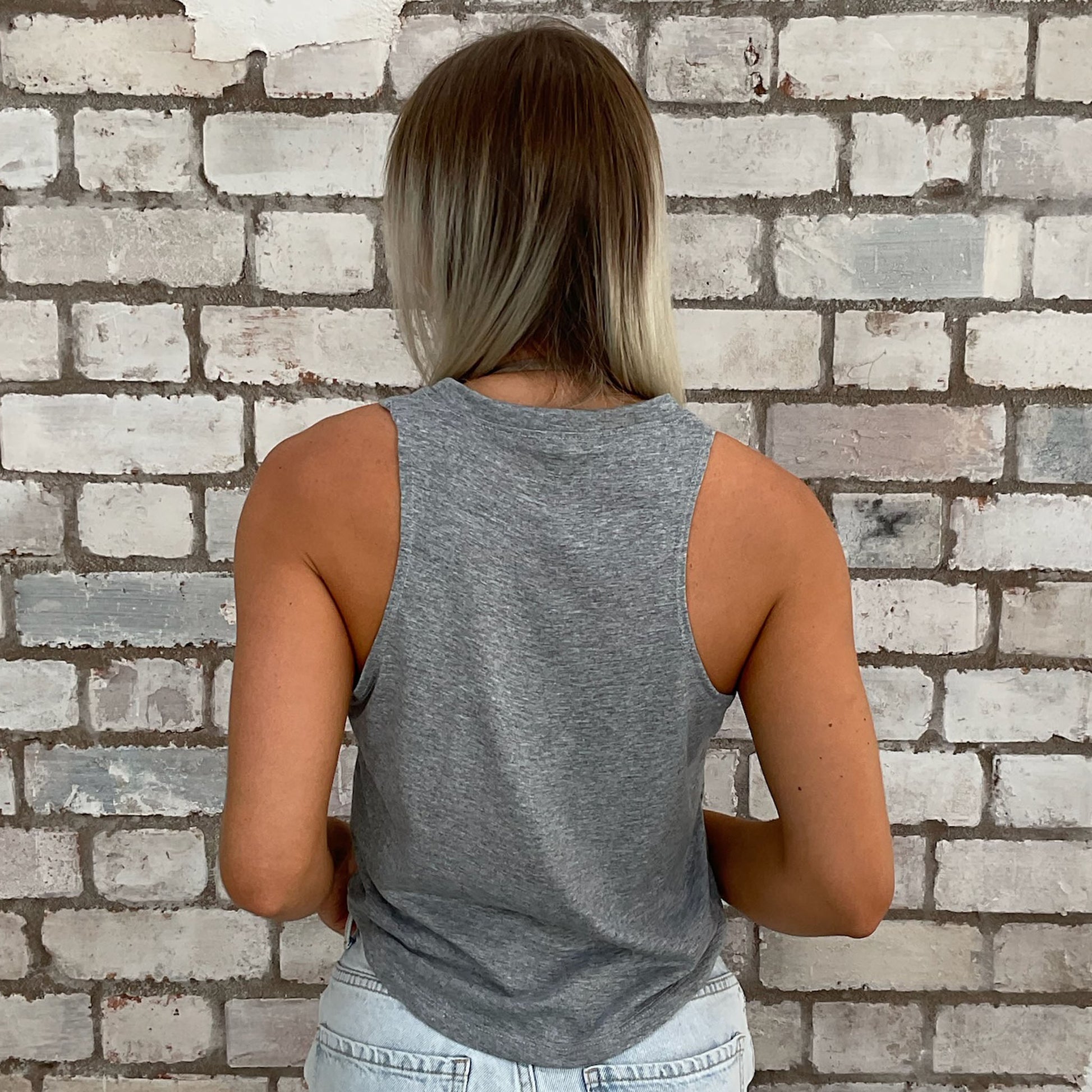 Person wearing a gray tank top against a brick wall, sustainable fashion
upcycled clothing
eco-friendly fashion
reworked fashion
ethical clothing brand
slow fashion