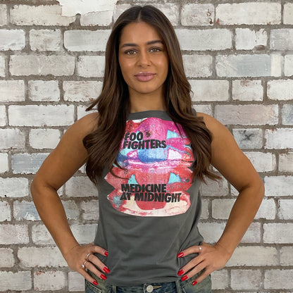 Woman wearing a tank top with Foo Fighters graphic design against a brick wall.  sustainable fashion
upcycled clothing
eco-friendly fashion
reworked fashion
ethical clothing brand
slow fashion