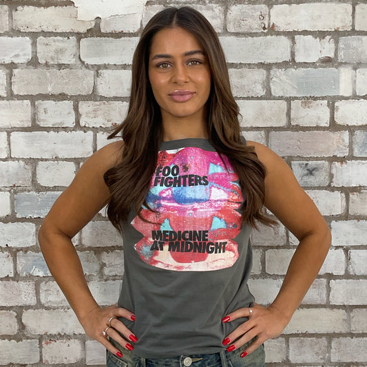Woman wearing a tank top with Foo Fighters graphic design against a brick wall.  sustainable fashion
upcycled clothing
eco-friendly fashion
reworked fashion
ethical clothing brand
slow fashion