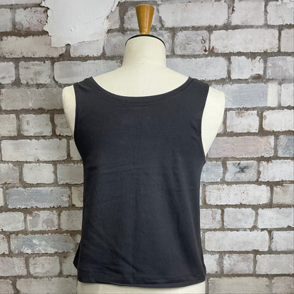Black sleeveless top on a mannequin against a brick wall.