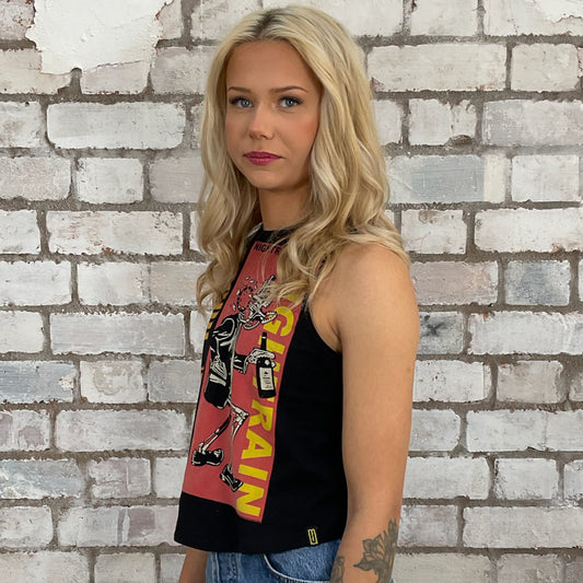 Woman wearing a sleeveless top with graphic design against a brick wall.  sustainable fashion UK
upcycled clothing UK
ethical clothing UK
made in Britain fashion
sustainable tank tops UK