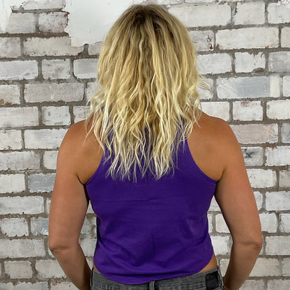 Person wearing a purple tank top and gray pants standing in front of a textured white brick wall. Lazy Text tank top, Lazy Purple vest, Message Lazy Unwantees