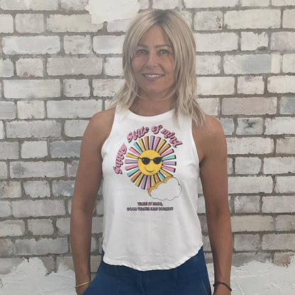 Woman wearing a white tank top with a colorful graphic design against a light brick wall.  sustainable fashion UK
eco-friendly clothing UK
upcycled t-shirts / upcycled tank tops
ethical fashion brand UK
zero waste clothing
slow fashion brand
made in Britain clothing
sustainable vest tops