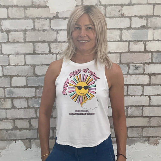 Woman wearing a white tank top with a colorful graphic design against a light brick wall.  sustainable fashion UK
eco-friendly clothing UK
upcycled t-shirts / upcycled tank tops
ethical fashion brand UK
zero waste clothing
slow fashion brand
made in Britain clothing
sustainable vest tops