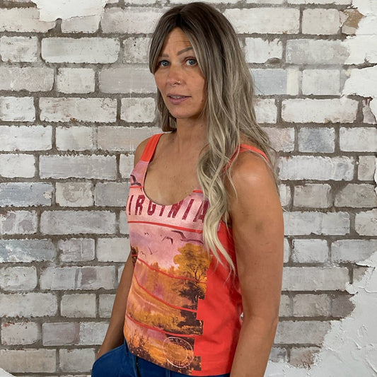 Woman wearing a colorful tank top with a scenic nature design against a white brick wall.  Unwantees Virginia Graphic print tank top, Virginia State Vest, Up Cycled fashion by Unwantees