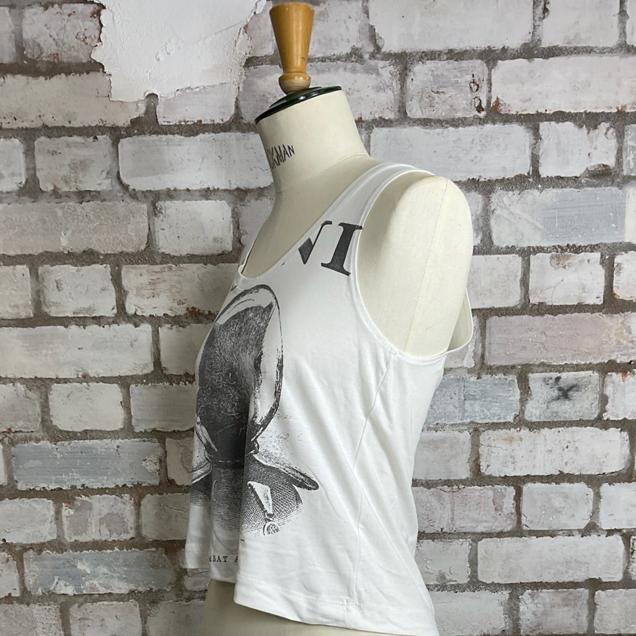 White sleeveless top with elephant design on a mannequin against a brick wall.  White tank top with graphic design on a mannequin against a brick wall.  Wombat Astronaut, Plini Band Tshirt, Plini Tank Top, Plini Vest Top, Plini Tank Top, Wombat print tank top