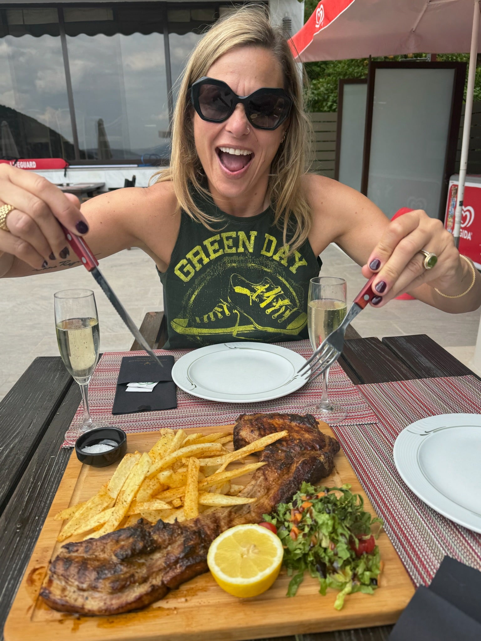 Woman eating a meal while wearing a Green Day graphic Unwantee tank top