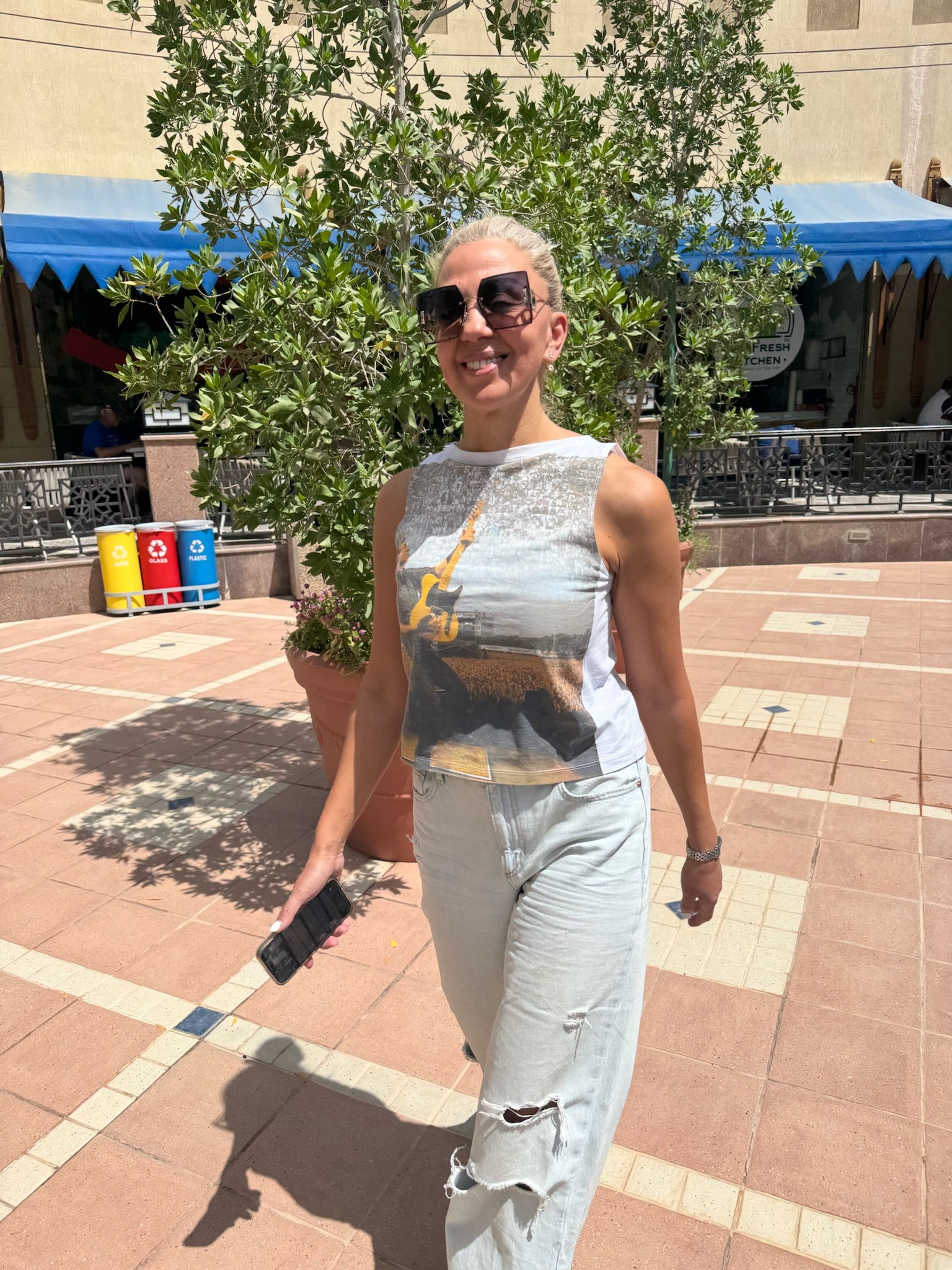 Woman walking outdoors wearing a concert graphic Unwantee tank top